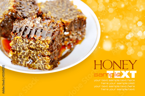 Photo: Sweet honeycombs with honey on plate on a yellow background Sweet honeycombs with honey on plate on a yellow background