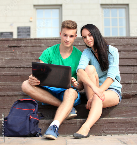 Photo: Two students studying with computer notebook outdoors Two students studying with computer notebook outdoors