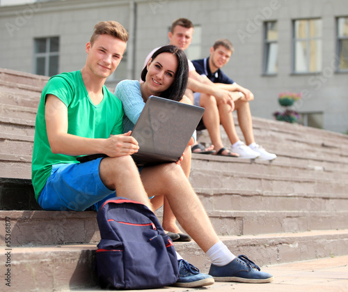 Photo: Two students studying with computer notebook outdoors Two students studying with computer notebook outdoors