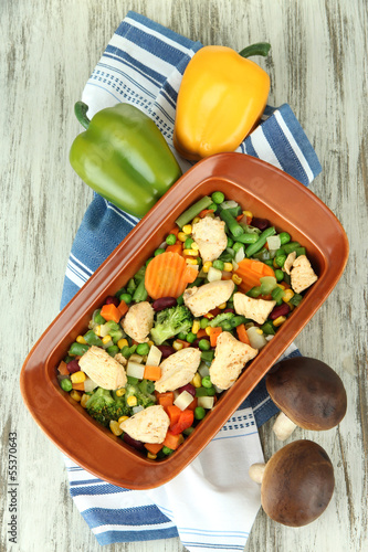 Photo: Casserole with vegetables and meat, on wooden background Casserole with vegetables and meat, on wooden background