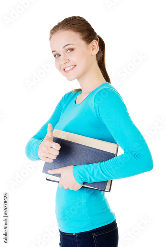 Photo: Attractive young student woman with book gesturing OK Attractive young student woman with book gesturing OK