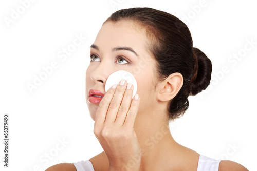 Photo: Portrait of happy young woman cleaning skin by cotton pad Portrait of happy young woman cleaning skin by cotton pad