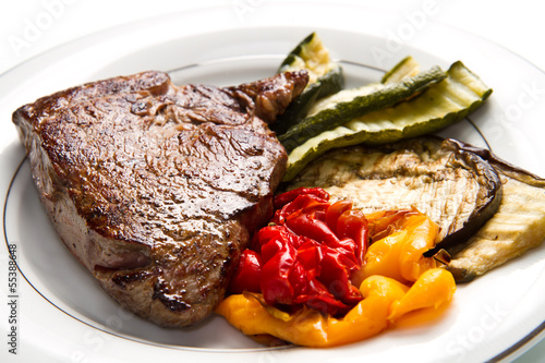 Photo: Delicious beef steaks on white dish with grilled vegetables Delicious beef steaks on white dish with grilled vegetables