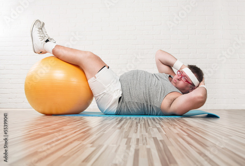 Photo: Funny overweight man working out in the gym Funny overweight man working out in the gym