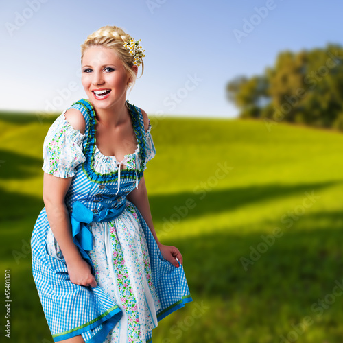 Photo: junge blonde Frau im Dirndl vor ländlichem Hintergrund junge blonde Frau im Dirndl vor ländlichem Hintergrund
