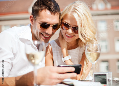 Photo: couple looking at smartphone in cafe couple looking at smartphone in cafe
