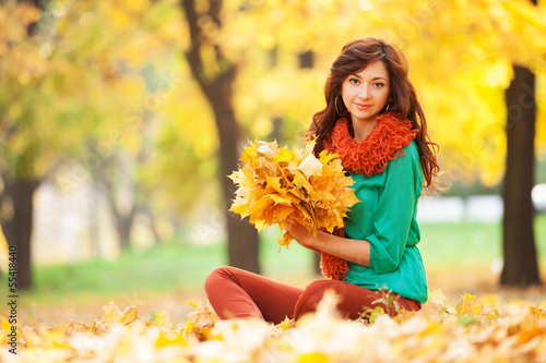 Photo: Young pretty woman relaxing in the autumn park Young pretty woman relaxing in the autumn park