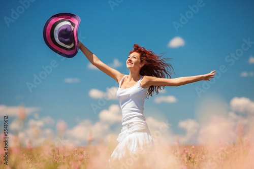 Photo: Cute woman running in the field with flowers Cute woman running in the field with flowers
