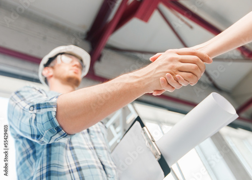 Photo: builder with blueprint shaking partner hand builder with blueprint shaking partner hand