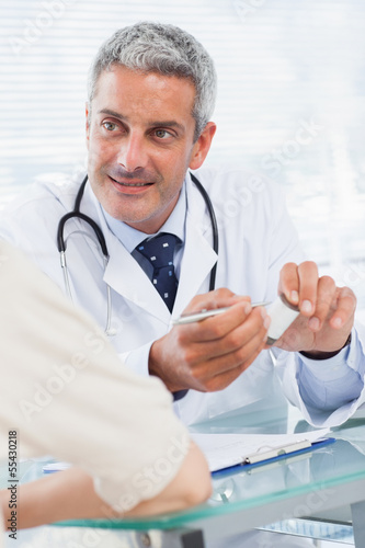 Photo: Smiling doctor listening to his patient Smiling doctor listening to his patient
