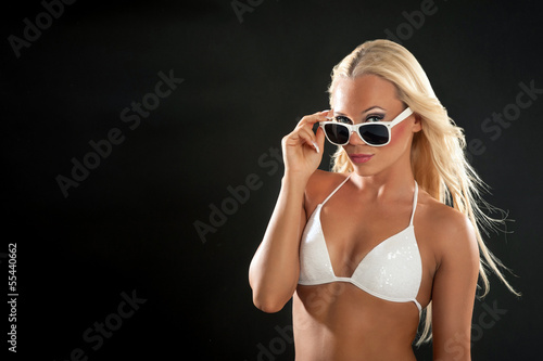 Photo: Beautiful blonde woman portrait with white bikini and sunglasses Beautiful blonde woman portrait with white bikini and sunglasses