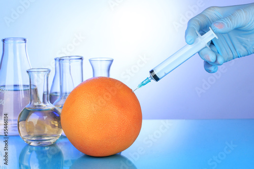 Photo: Injection into fresh grapefruit on blue background Injection into fresh grapefruit on blue background