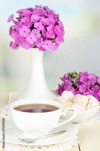 Photo: Beautiful bouquet of phlox with cup of tea Beautiful bouquet of phlox with cup of tea