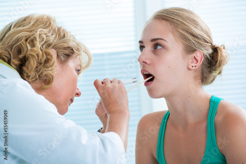 Photo: Doctor checking with depressor sore throat to teenage girl Doctor checking with depressor sore throat to teenage girl