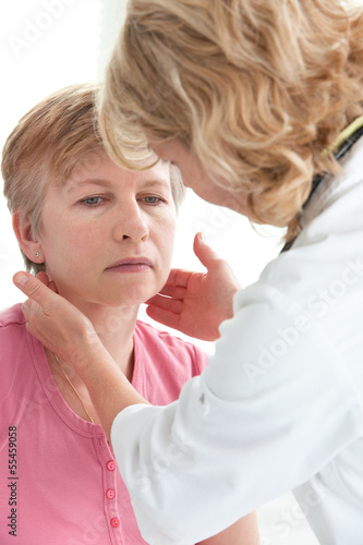 Photo: female doctor touching the throat of a patient in the office female doctor touching the throat of a patient in the office