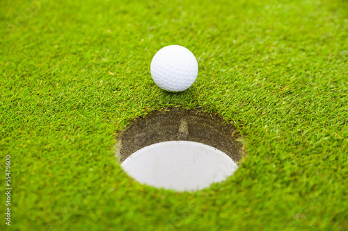 Photo: golf ball on lip of cup. golf ball on lip of cup.