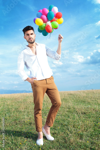 Photo: casual man with balloons and hand in pocket casual man with balloons and hand in pocket