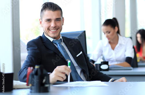 Photo: Happy businessman sitting in office Happy businessman sitting in office