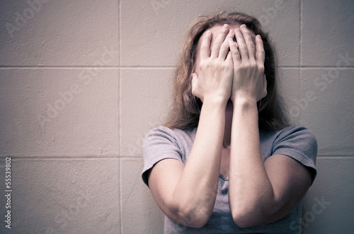 Photo: one sad woman sitting on the floor near a wall and holding her h one sad woman sitting on the floor near a wall and holding her h