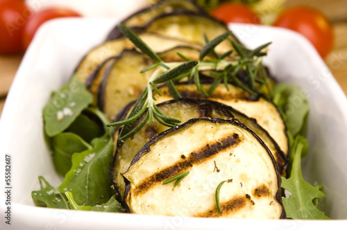 Photo: Grilled eggplant slices on a plate with fresh rosemary Grilled eggplant slices on a plate with fresh rosemary