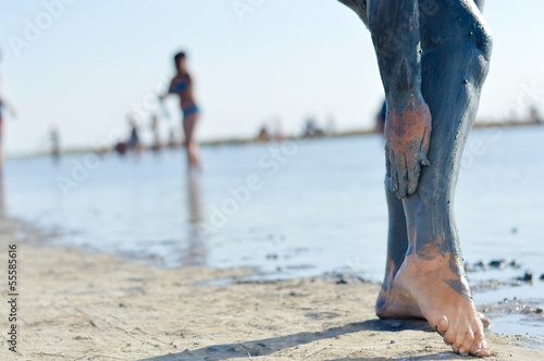 Photo: Woman applying mineral blue mud on legs at Sivash lake Woman applying mineral blue mud on legs at Sivash lake