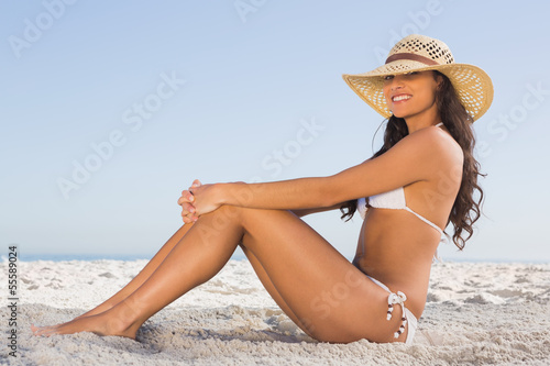 Photo: Attractive brunette in white bikini posing while sitting Attractive brunette in white bikini posing while sitting