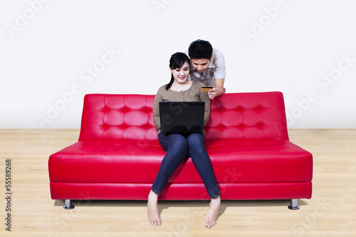 Photo: Asian couple pay online using credit card at home Asian couple pay online using credit card at home