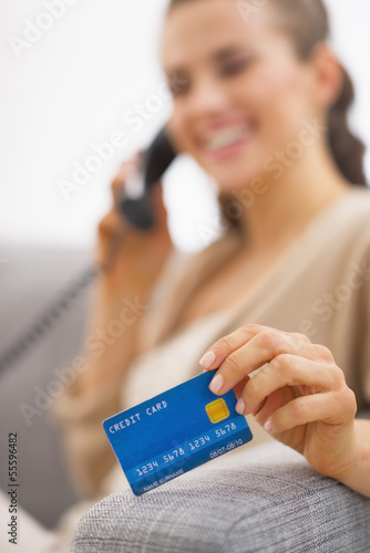 Photo: Closeup on credit card in hand of young woman talking phone Closeup on credit card in hand of young woman talking phone