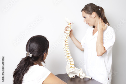 Photo: ärztin zeigt Patientin Modell einer Wirbelsäule ärztin zeigt Patientin Modell einer Wirbelsäule