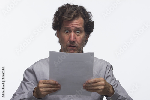 Photo: Business man reading report looking shocked, horizontal Business man reading report looking shocked, horizontal