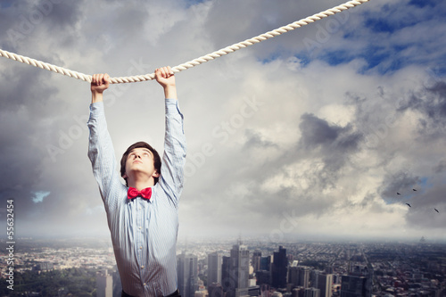 Photo: Businessman hanging on rope Businessman hanging on rope