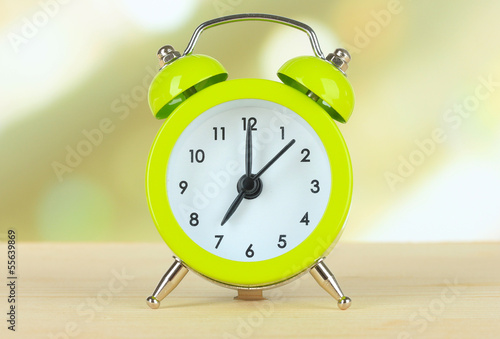 Photo: Alarm clock on table on light background Alarm clock on table on light background