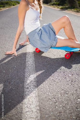 Photo: Body of young woman sitting on her skateboard Body of young woman sitting on her skateboard