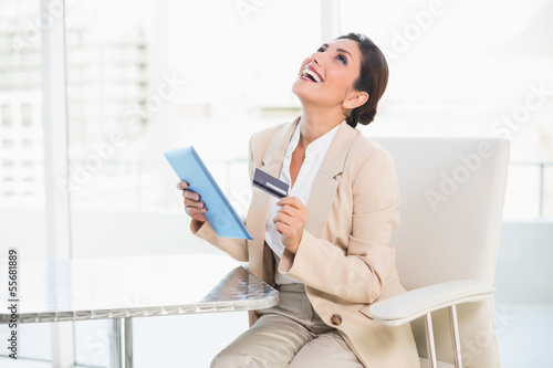 Photo: Laughing businesswoman shopping online with tablet pc Laughing businesswoman shopping online with tablet pc
