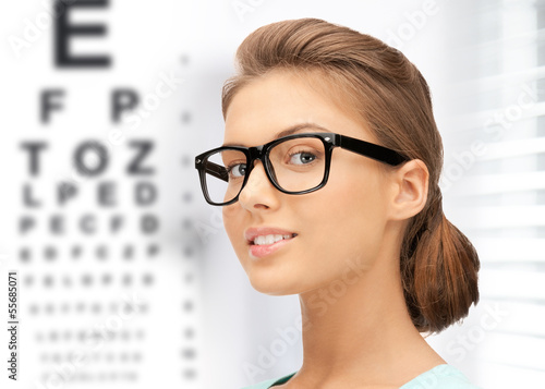 Photo: woman in eyeglasses with eye chart woman in eyeglasses with eye chart