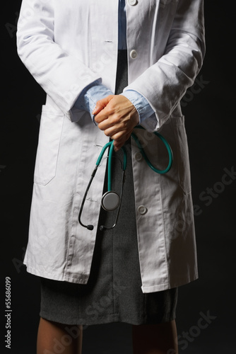 Photo: Closeup on stethoscope in hand of doctor woman isolated on black Closeup on stethoscope in hand of doctor woman isolated on black