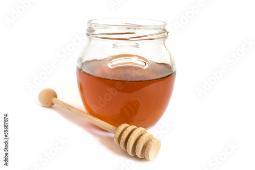 Photo: Honey dipper next to a jar of honey Honey dipper next to a jar of honey