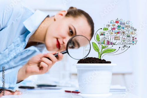 Photo: Businesswoman examining sprout Businesswoman examining sprout