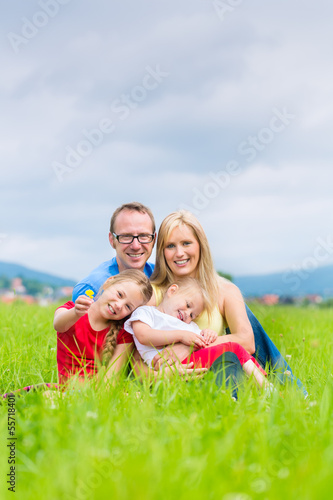 Photo: Happy Family outdoors sitting on grass Happy Family outdoors sitting on grass