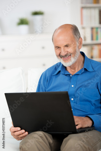 Photo: älterer mann mit laptop auf dem sofa älterer mann mit laptop auf dem sofa