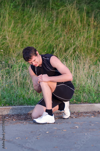 Photo: Sportsman holding his leg. Sports injury concept. Sportsman holding his leg. Sports injury concept.