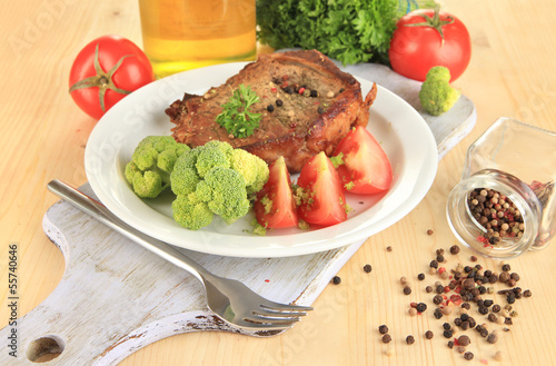 Photo: Piece of fried meat on plate on wooden table close-up Piece of fried meat on plate on wooden table close-up