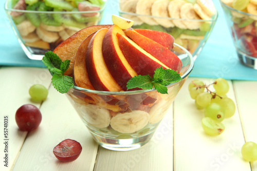 Photo: Tasty fruit salad in glass bowls, on white wooden table Tasty fruit salad in glass bowls, on white wooden table