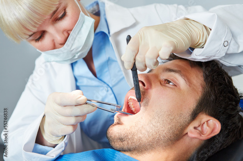 Photo: Dentist giving dental treatment to man Dentist giving dental treatment to man