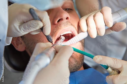 Photo: Hands of dentist at dental treatment Hands of dentist at dental treatment