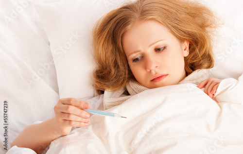 Photo: Woman with thermometer sick colds, flu, fever in bed Woman with thermometer sick colds, flu, fever in bed