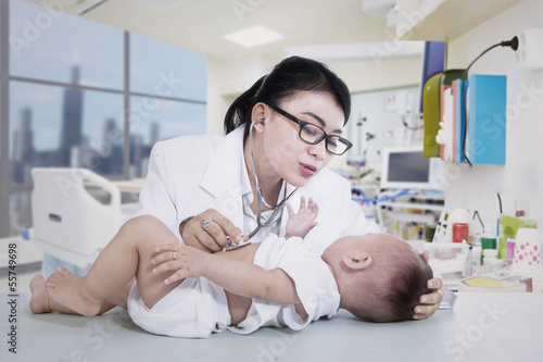 Photo: Beautiful doctor checking baby at clinic Beautiful doctor checking baby at clinic