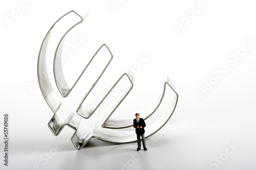 Photo: Geschäftsmann-Figur vor Euro-Symbol Geschäftsmann-Figur vor Euro-Symbol