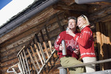 Photo: Italien, Südtirol, Seiseralm, Paar steht auf dem Dach einer Blockhütte mit Thermoskanne Italien, Südtirol, Seiseralm, Paar steht auf dem Dach einer Blockhütte mit Thermoskanne
