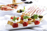 Photo: Grissini mit Parmaschinken und Oliven und Mozzarella mit Tomaten, italienische Vorspeisen Grissini mit Parmaschinken und Oliven und Mozzarella mit Tomaten, italienische Vorspeisen